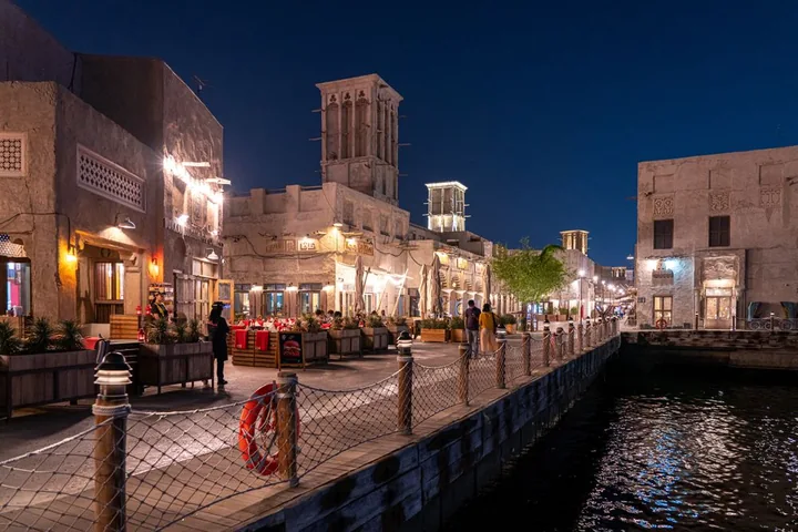 Traditional wind towers and illuminated waterfront buildings at Al Seef